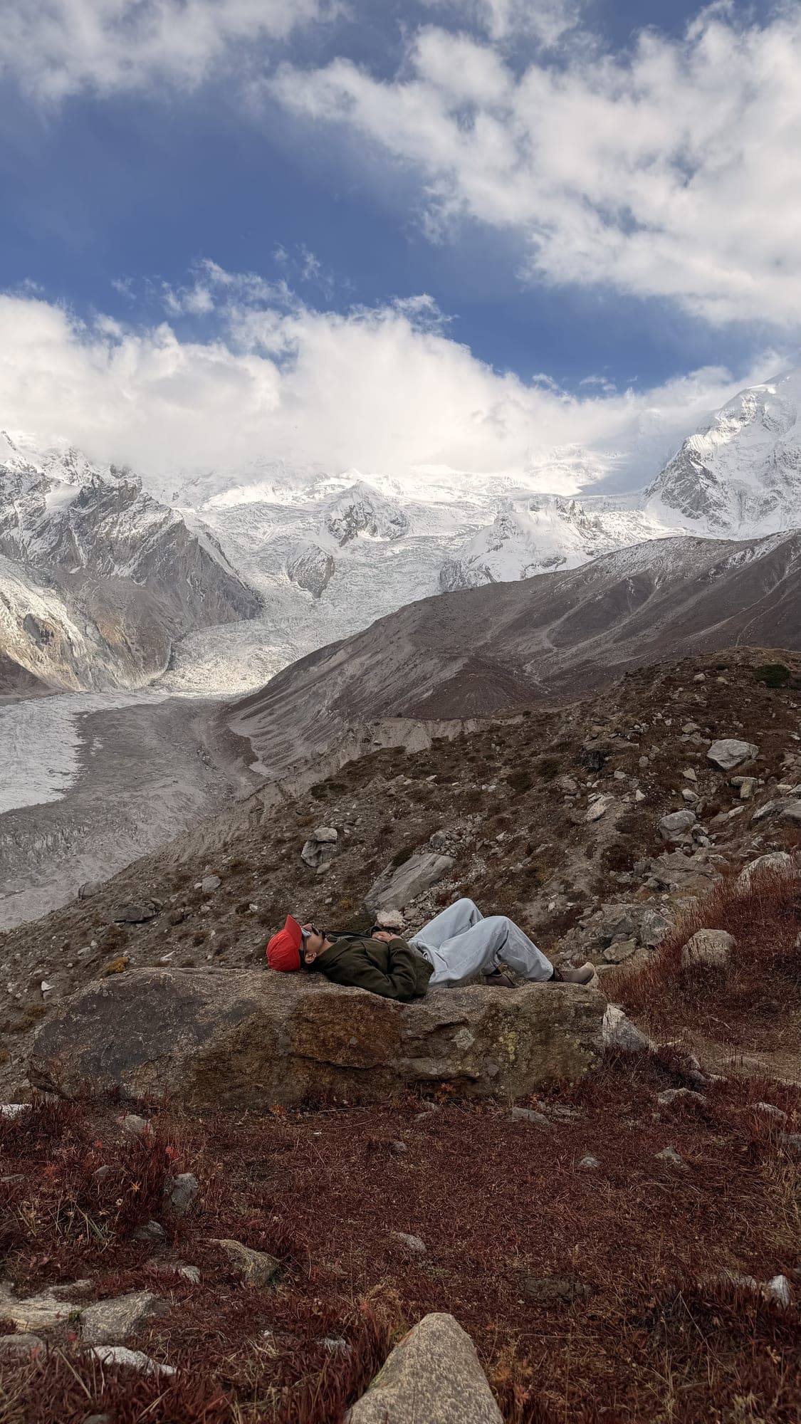 Snowy peaks above a glacier valley, a person resting on the rocks