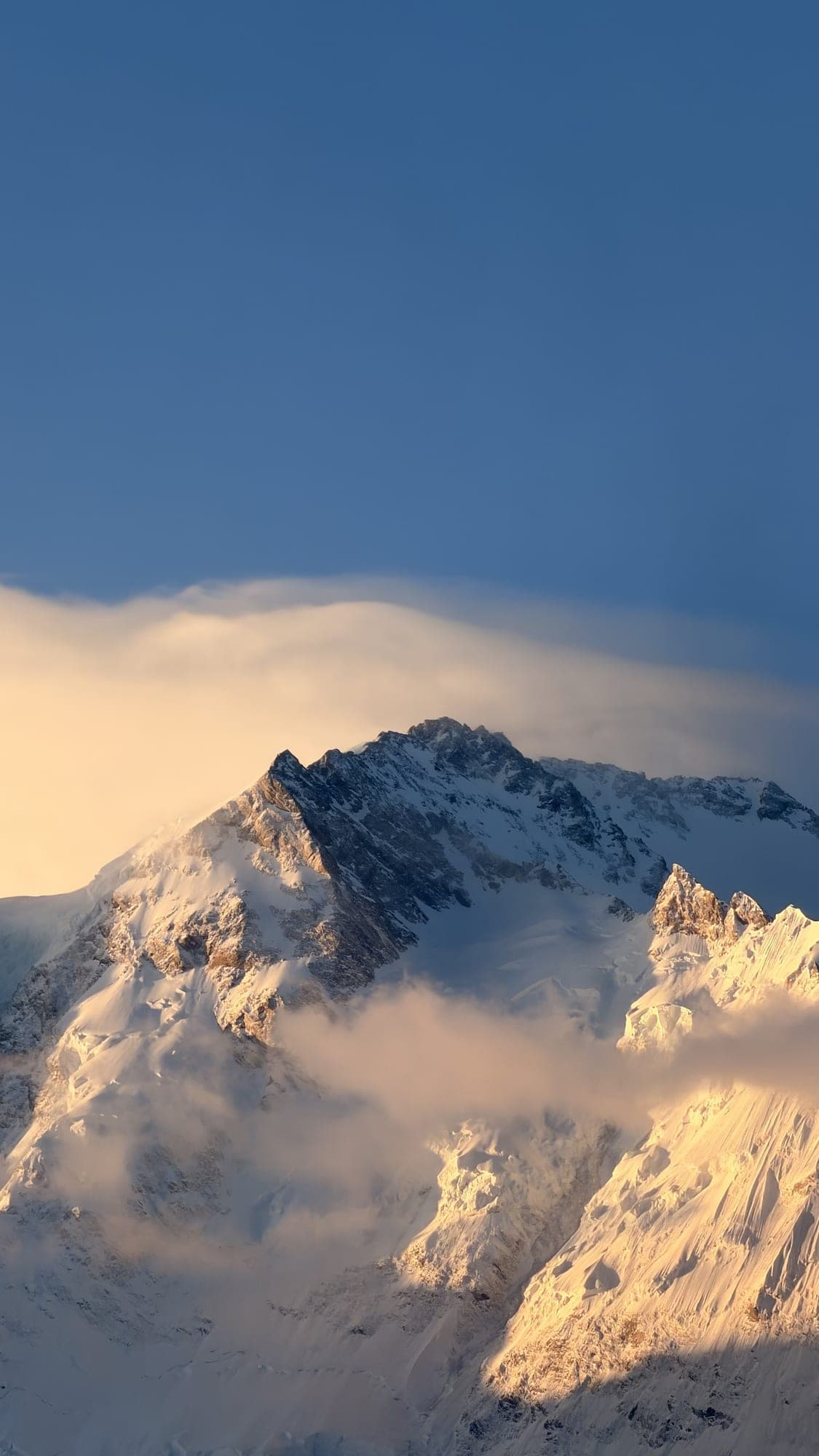 A snow peak lit at sunset above the clouds