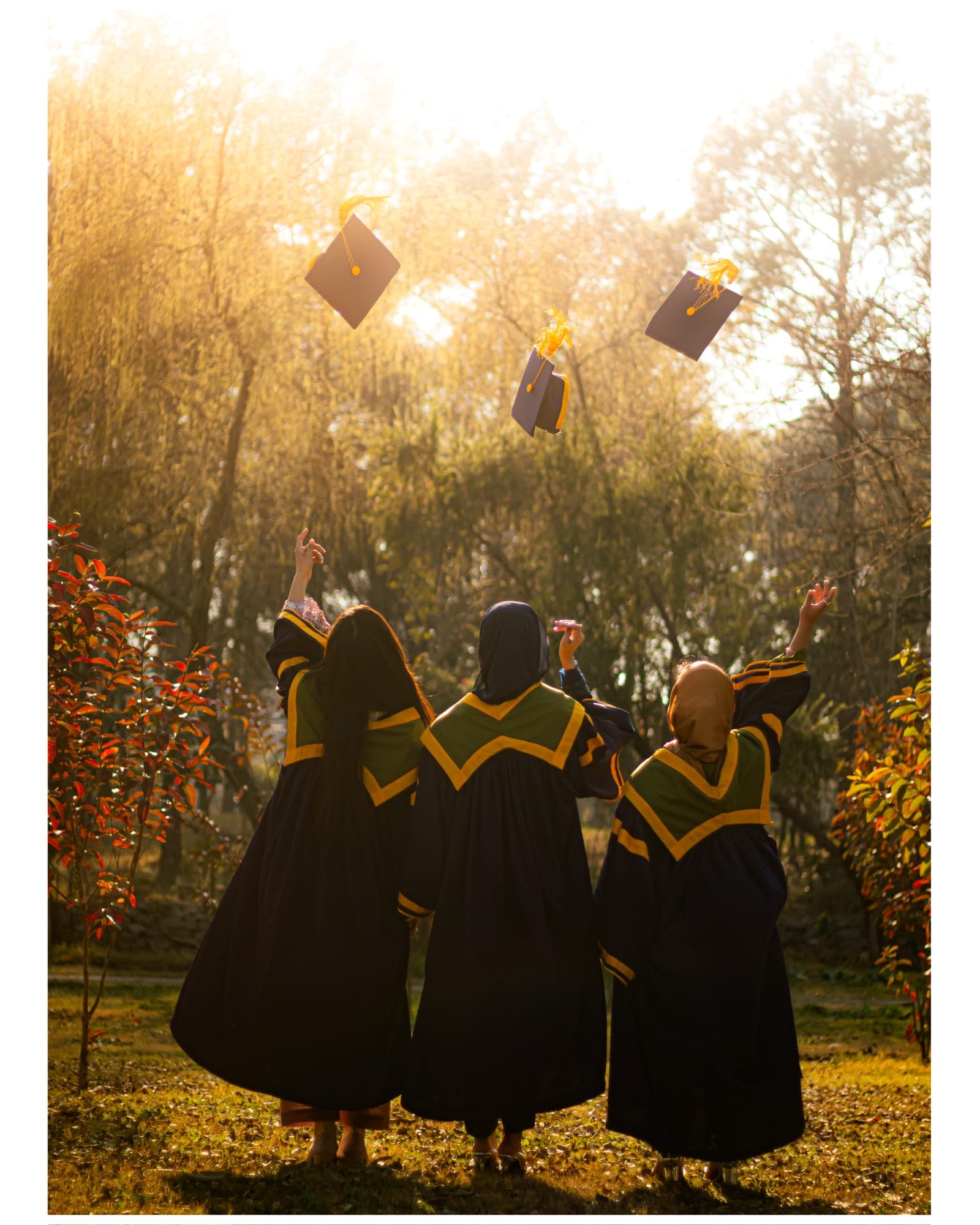 Graduates throwing their caps in golden autumn light